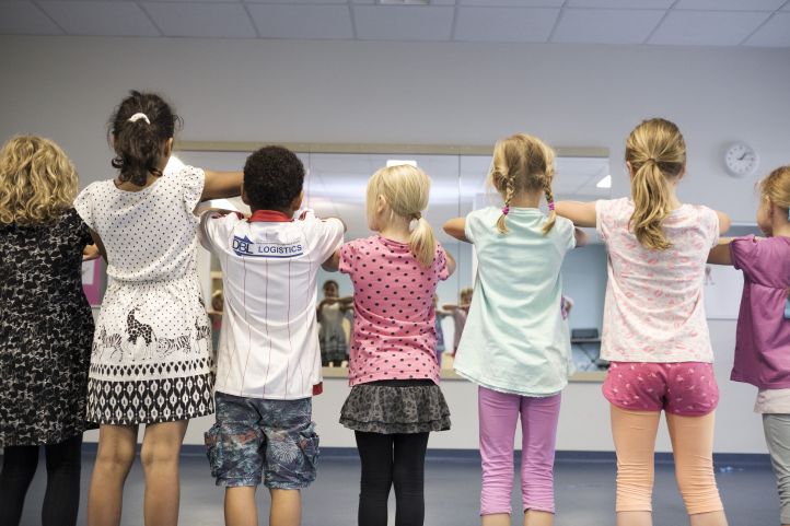 Kinder tanzen in einer Reihe mit dem Rücken zum Betrachter