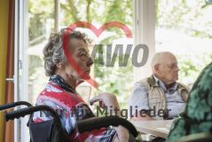 Eine alte Frau Seniorin in einem Rollstuhl sitzt neben anderen Seniorinnern und Senioren