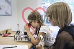 Ein Mädchen arbeitet mit einem Mikroskop