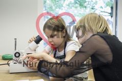 Zwei Mädchen arbeiten mit einem Mikroskop