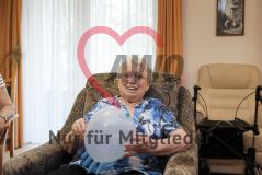 Eine alte Frau Seniorin mit einem Luftballon lächelt in die Kamera