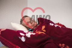 Eine alte Frau liegt zugedeckt im Bett eines Pflegeheims