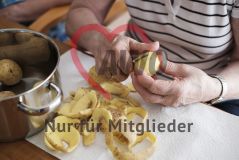 Eine alte Frau Seniorin schält Kartoffeln in einer Pflegeeinrichtung