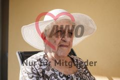 Eine alte Frau Seniorin mit Hut sitzt auf einem Balkon