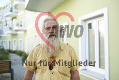 Ein alter Mann Senior steht vor einem Haus und blickt in die Kamera